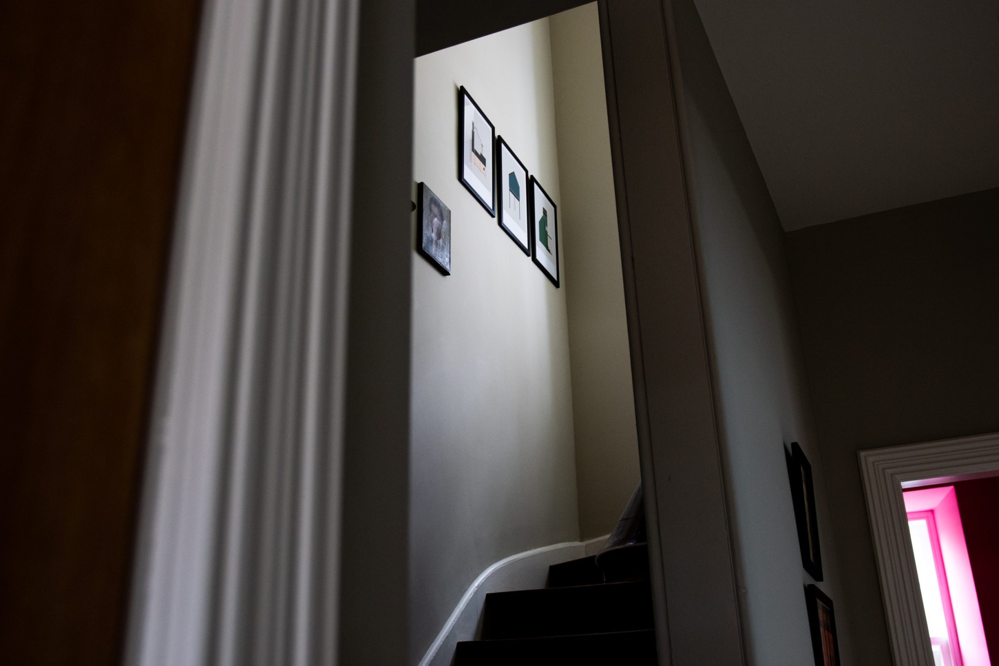 Photo taken of the interior of the North Lodge Cabin, showing the staircase with picture frames mounted on the side wall.