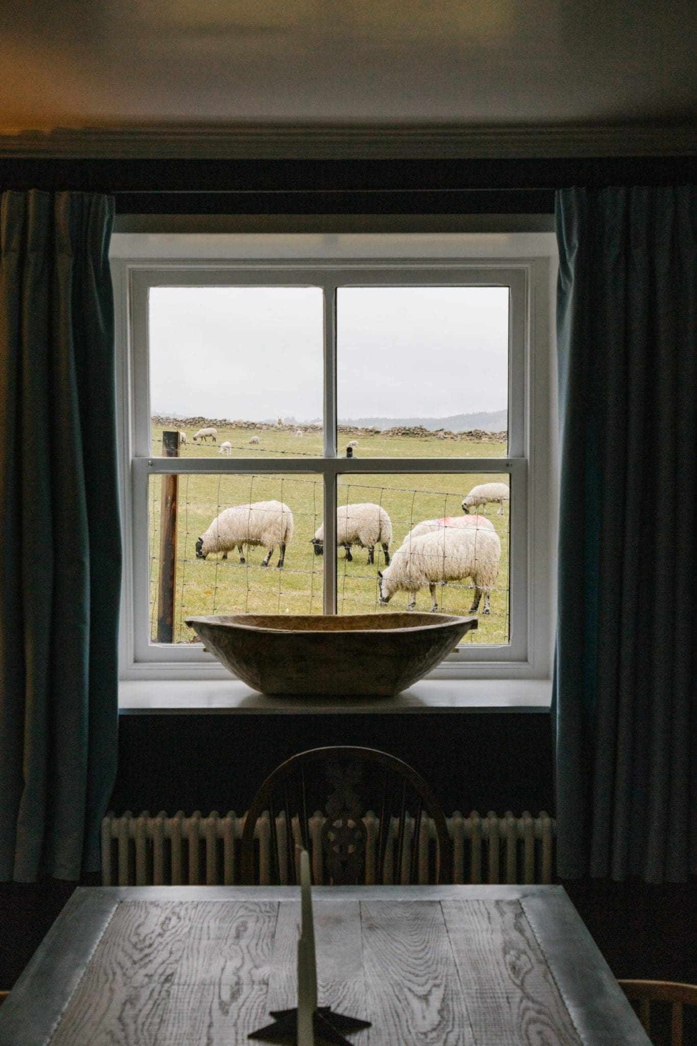 A photo taken of the view from the Cuttieshillock Cottage collection where you can see sheep wondering the fields.