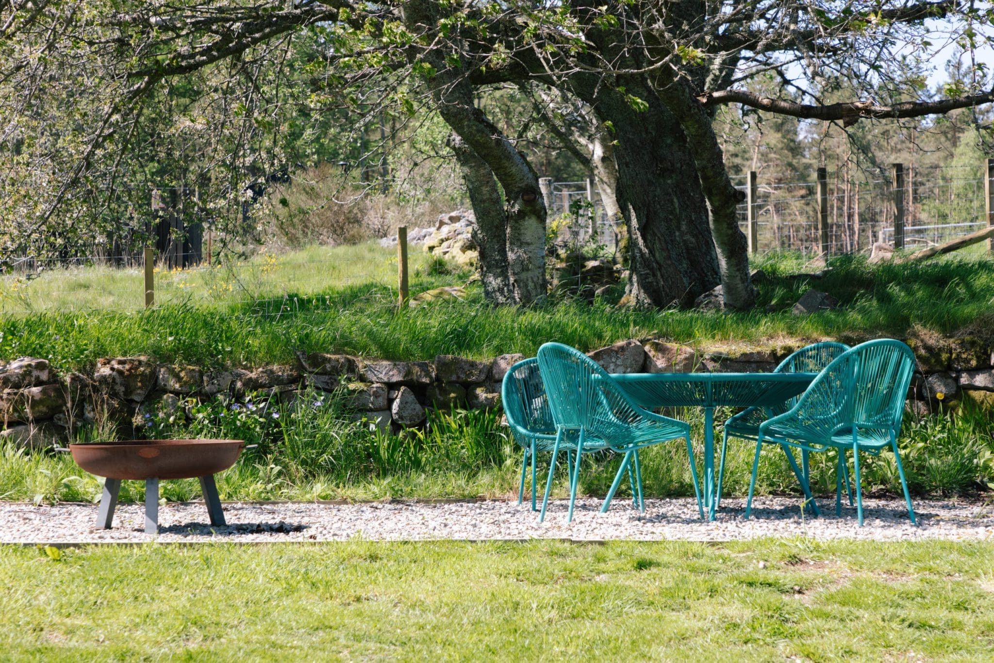 The outdoor space of Cuttieshillock Cottage with a view of their table and chairs and a fire pit not too far away.
