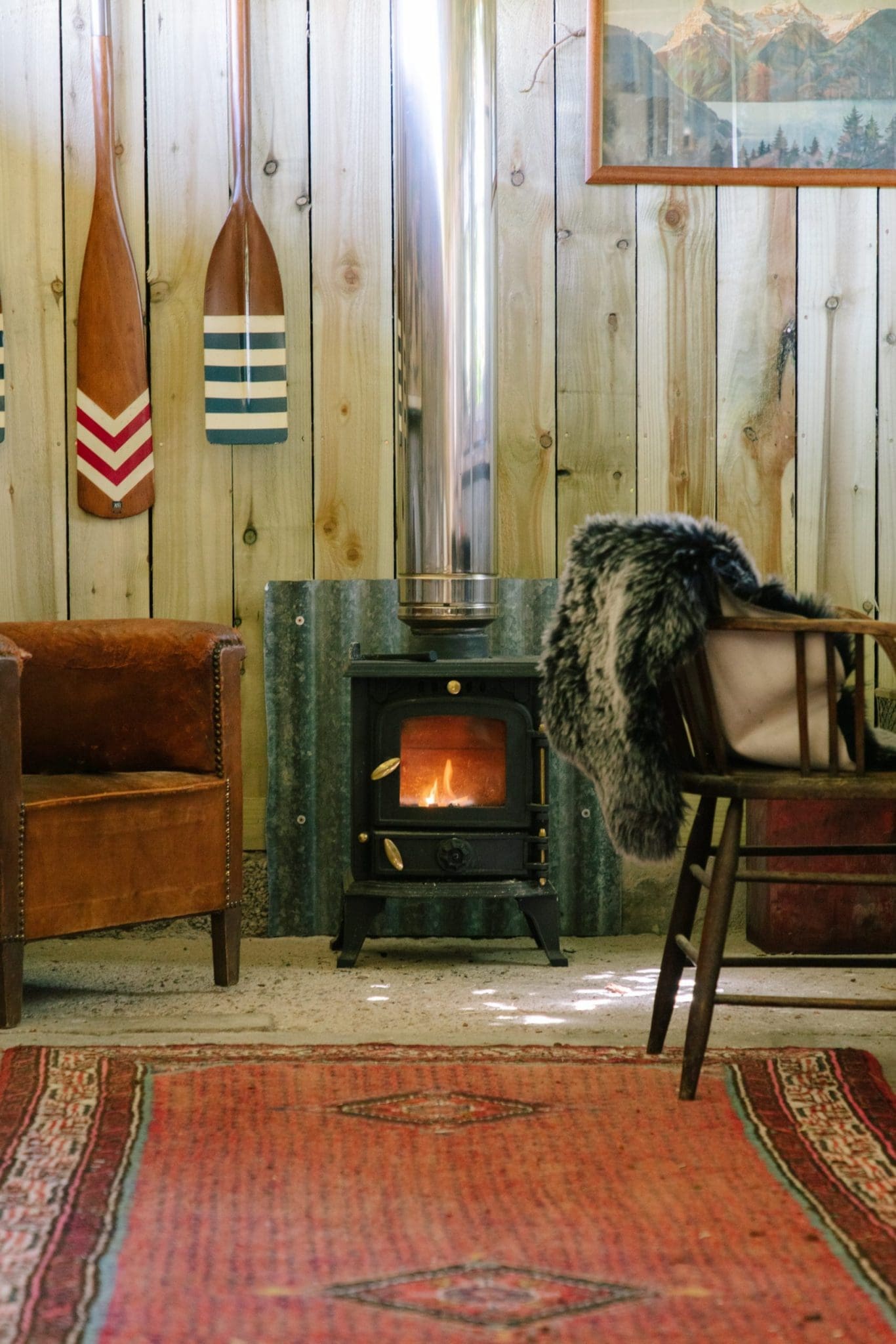 A lit wood burning fireplace with a view of some of the wall furniture, part of the Cuttieshillock cottage collection.