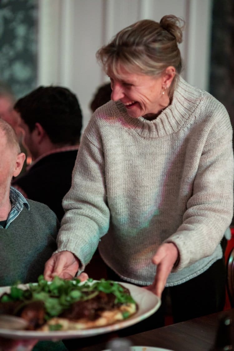 A guest serving a plate and enjoying herself at one of our seasonal feast events