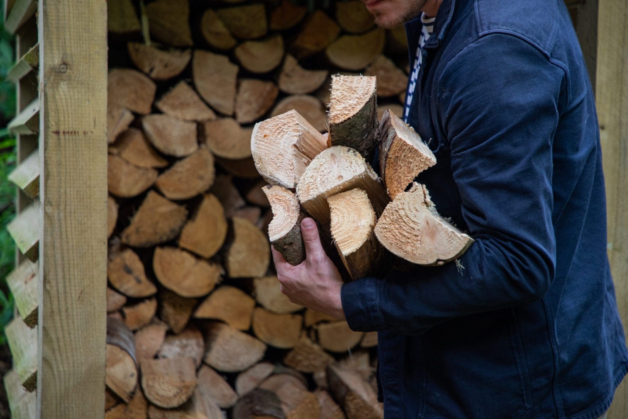 An image of a guest carry a large amount of chopped wood for a fire from the North Lodge Cabin collection.