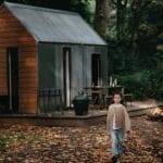 A child walking through the grounds of Glen dye, surrounded by fallen leaves with a cabin in the background.
