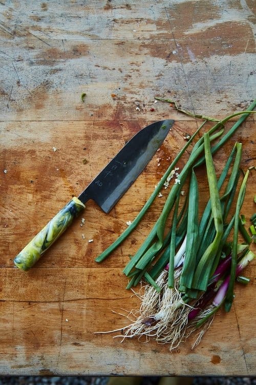 Top down view of a chopping board and knife, ready to cut spring onions for the seasonal feast event